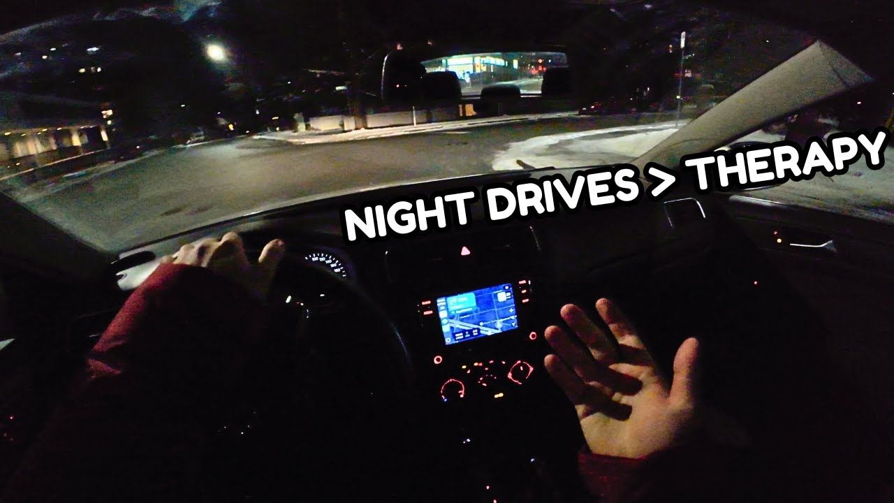 POV from a car driving at night with city lights ahead